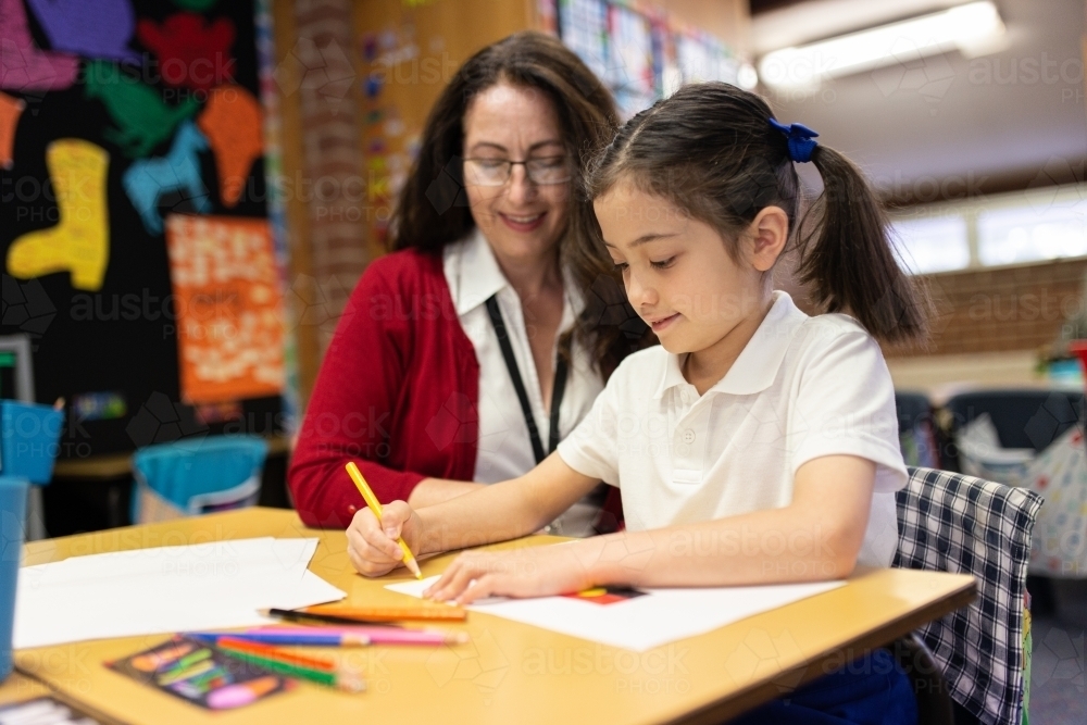 Female Teacher Helping Young Schoolgirl Draw - Australian Stock Image