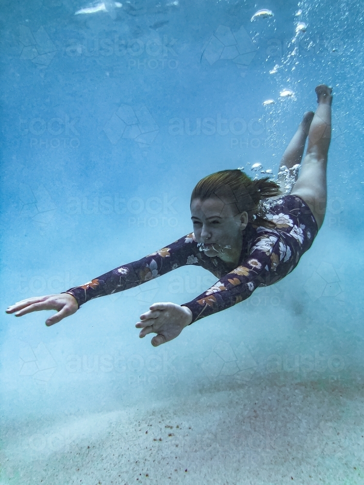 Female underwater in ocean wearing full piece swimsuit - Australian Stock Image