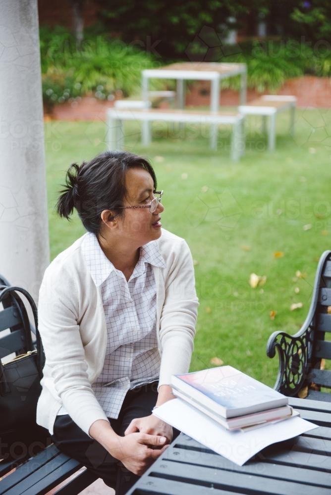 Female university teacher having a discussion at a bench in the garden - Australian Stock Image