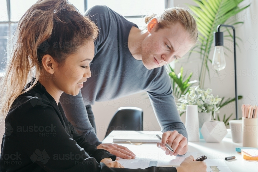 Female worker explaining something to a male team member - Australian Stock Image