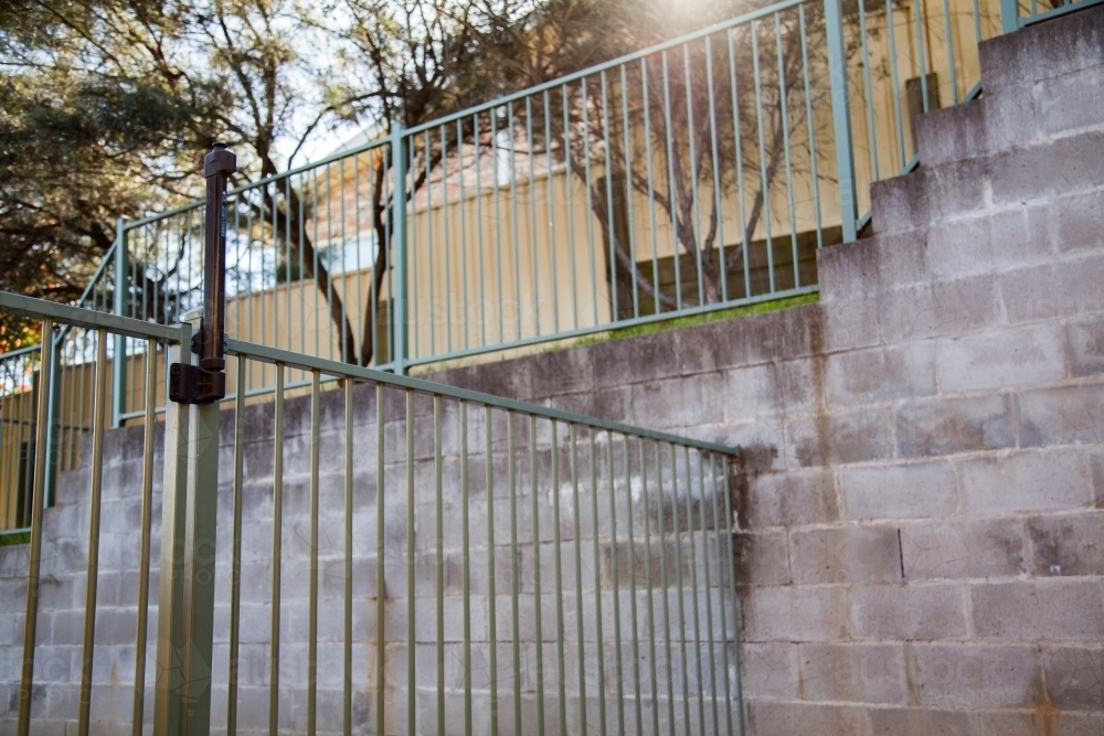 Fence beside brick wall with self closing gate - Australian Stock Image