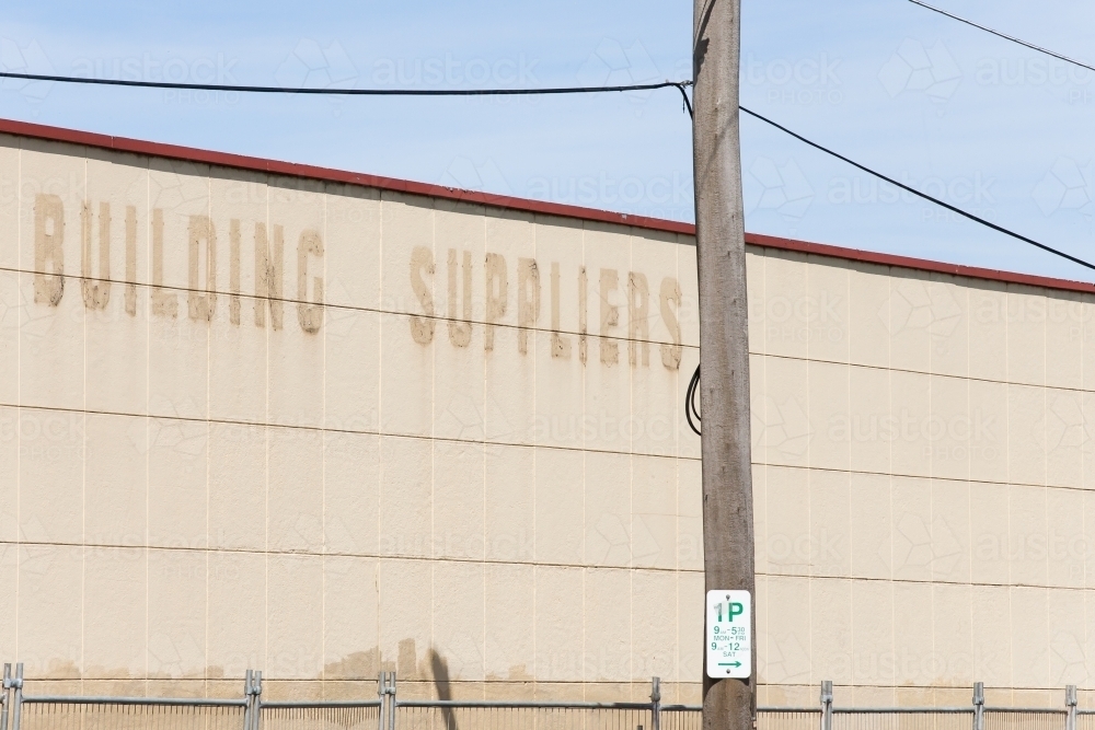 Fenced off wall of old building with faded signage - Australian Stock Image