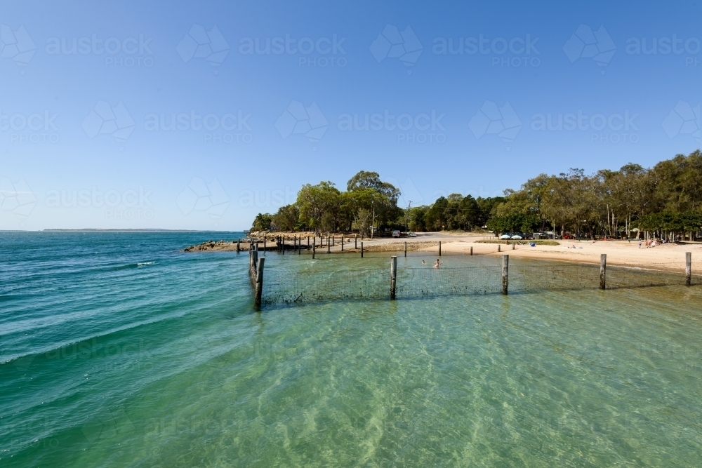 Fenced swimming enclosure at beach with clear blue green water - Australian Stock Image