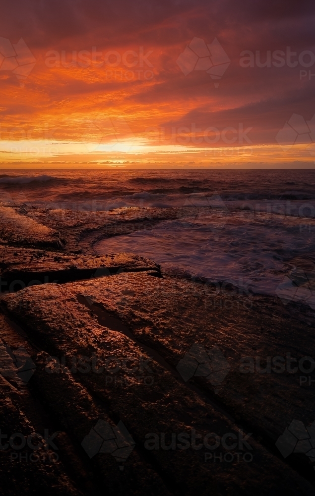Fiery Sunrise on a coastal rock formation - Australian Stock Image