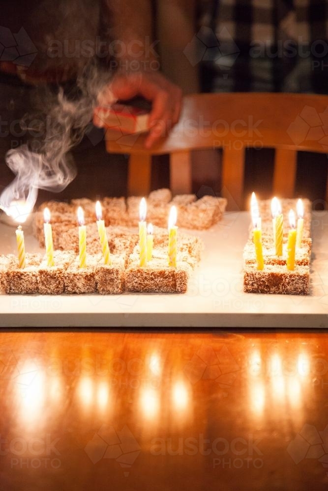 Fifteen birthday candles being lit on a lamington cake - Australian Stock Image
