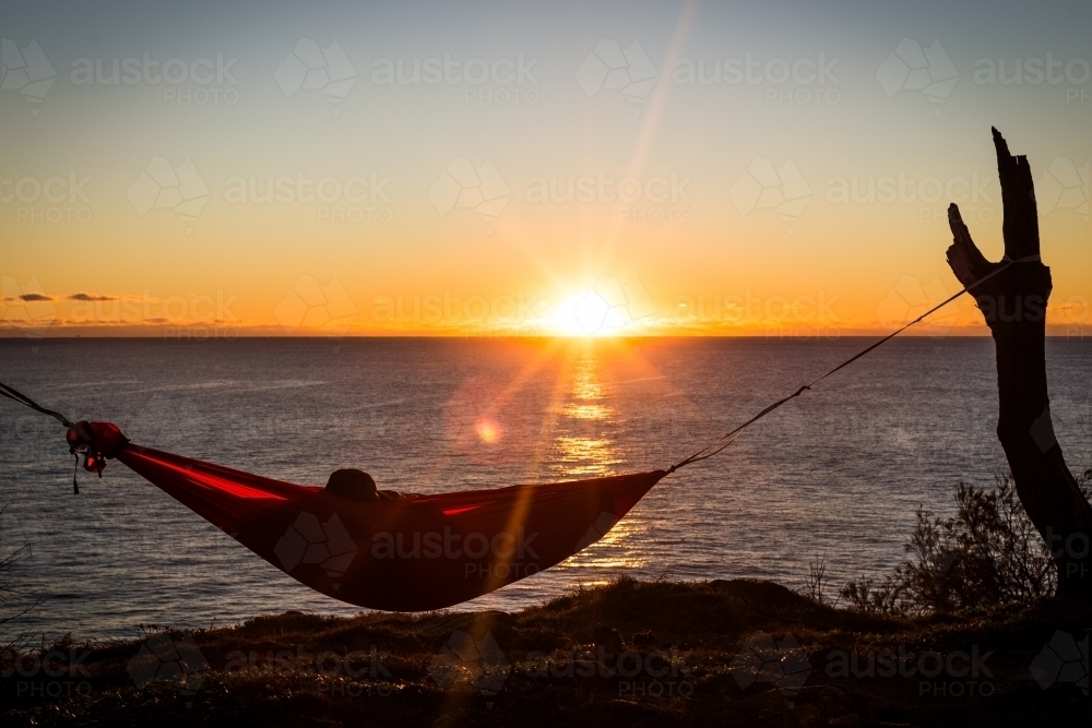Figure in a hammock overlooking the ocean - Australian Stock Image