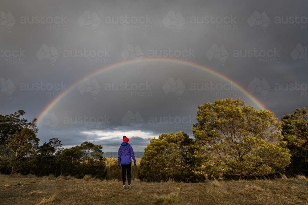 figure in nature looking towards a rainbow - Australian Stock Image