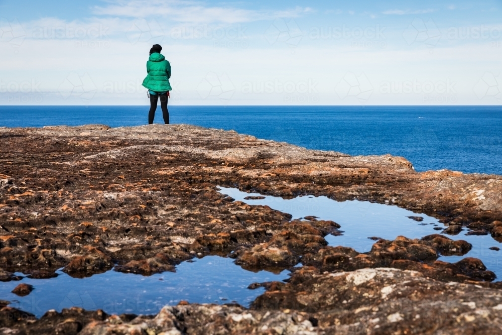 figure standing on rocks overlooking the ocean - Australian Stock Image