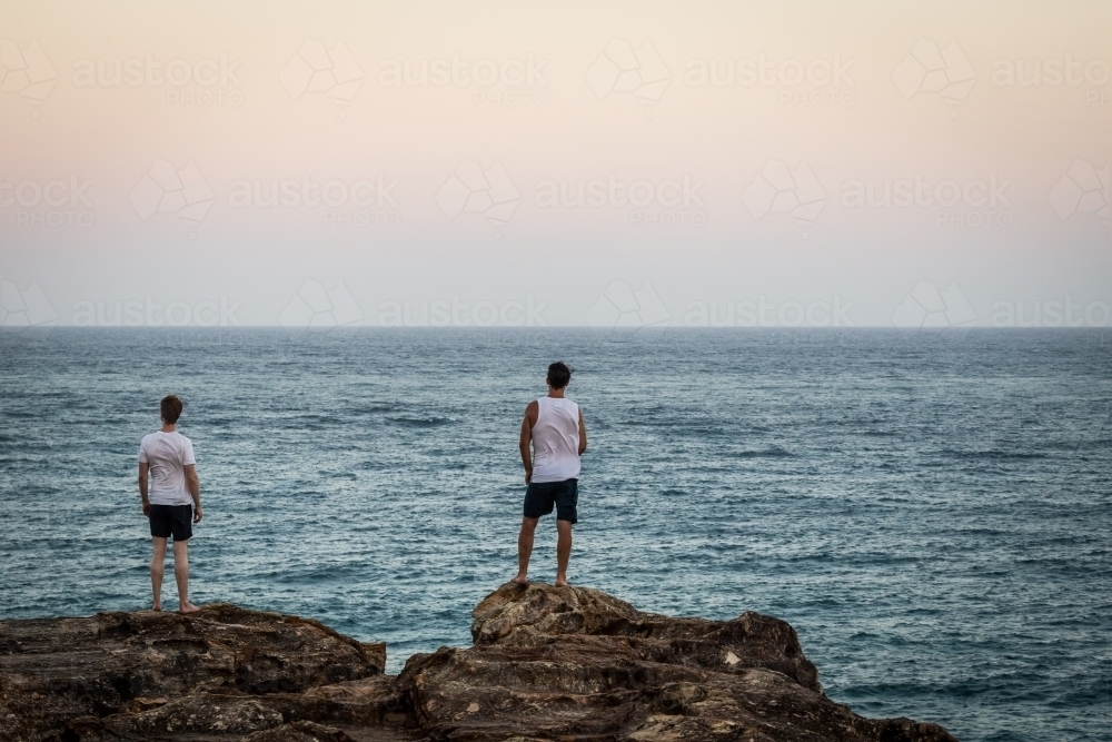 Image of Figures overlooking the ocean - Austockphoto