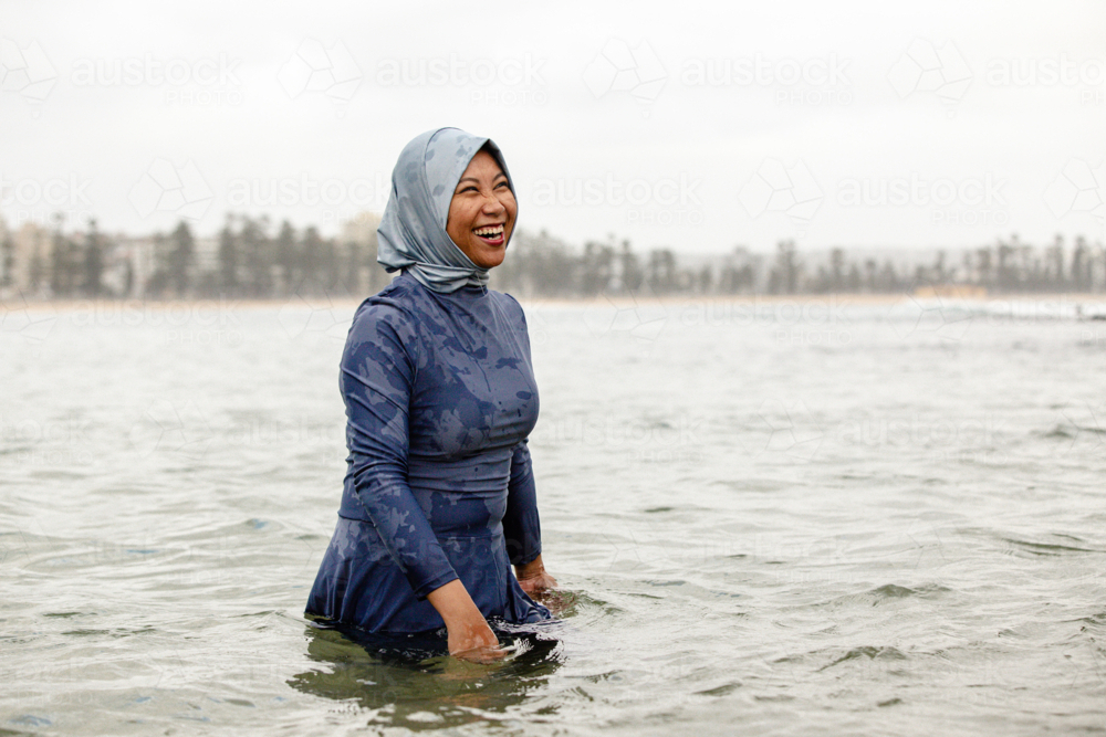 Filipina woman walking on shallow waters at the beach - Australian Stock Image