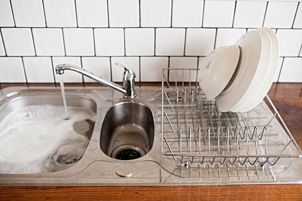Image of Filling the sink with washing up water to do the dishes