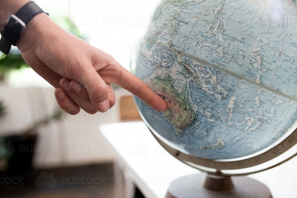 Finger pointing to map of Australia on round world globe - Australian Stock Image