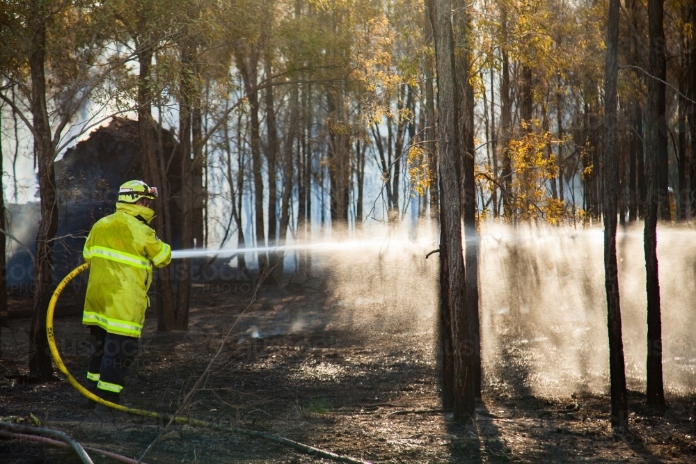 Fire and rescue fireman spraying water on a fire from hose - Australian Stock Image