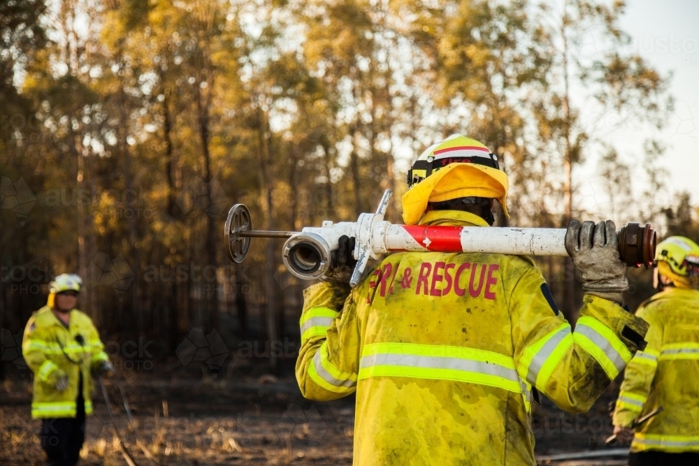 Fire and rescue man in fire brigade out at fire emergency site with water hydrant - Australian Stock Image