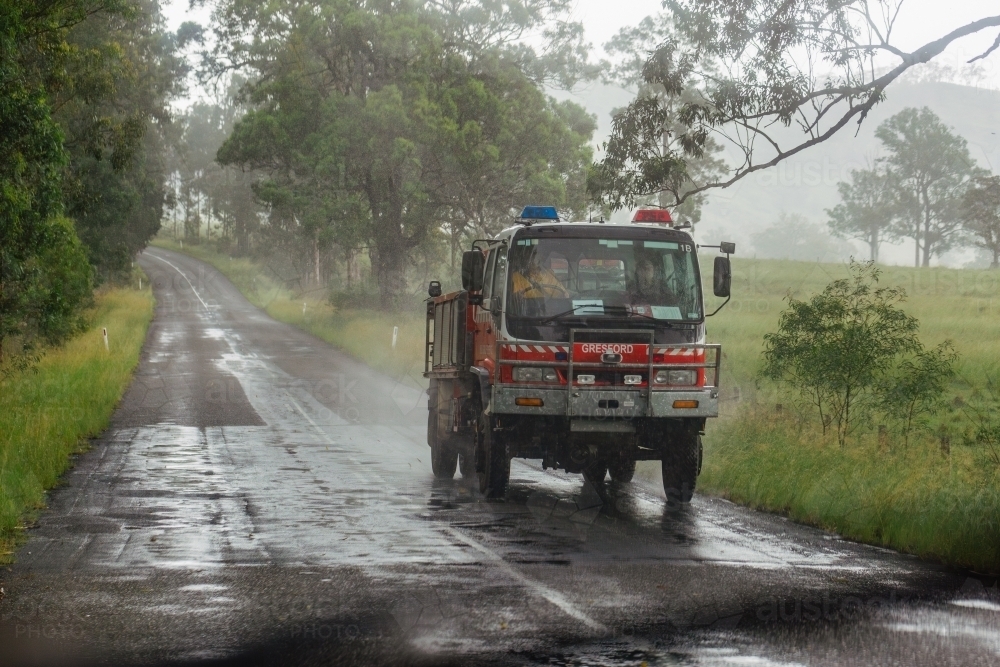 Image of Fire truck driving down country road on rainy day - Austockphoto