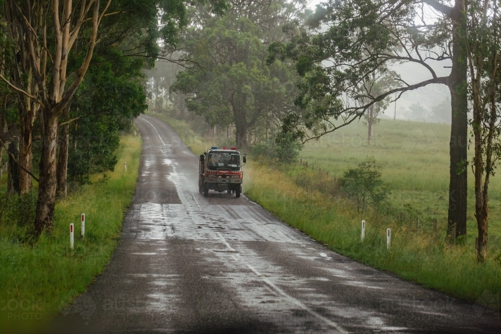 Image of Fire truck driving down country road on rainy day - Austockphoto