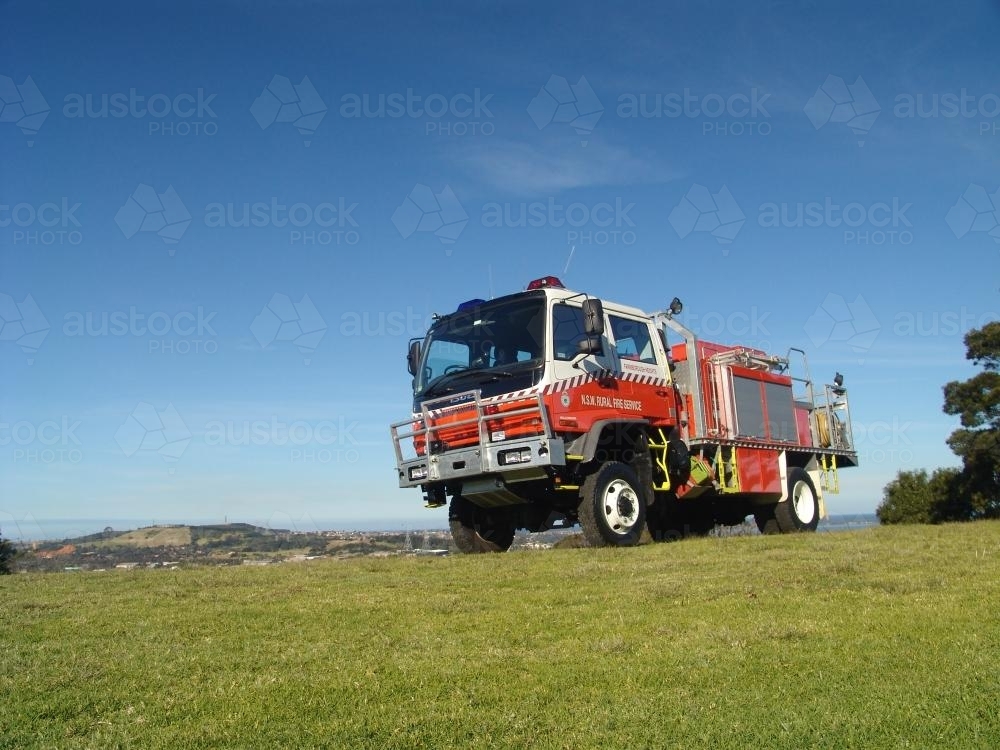 Fire truck on a green hilltop against a blue sky - Australian Stock Image
