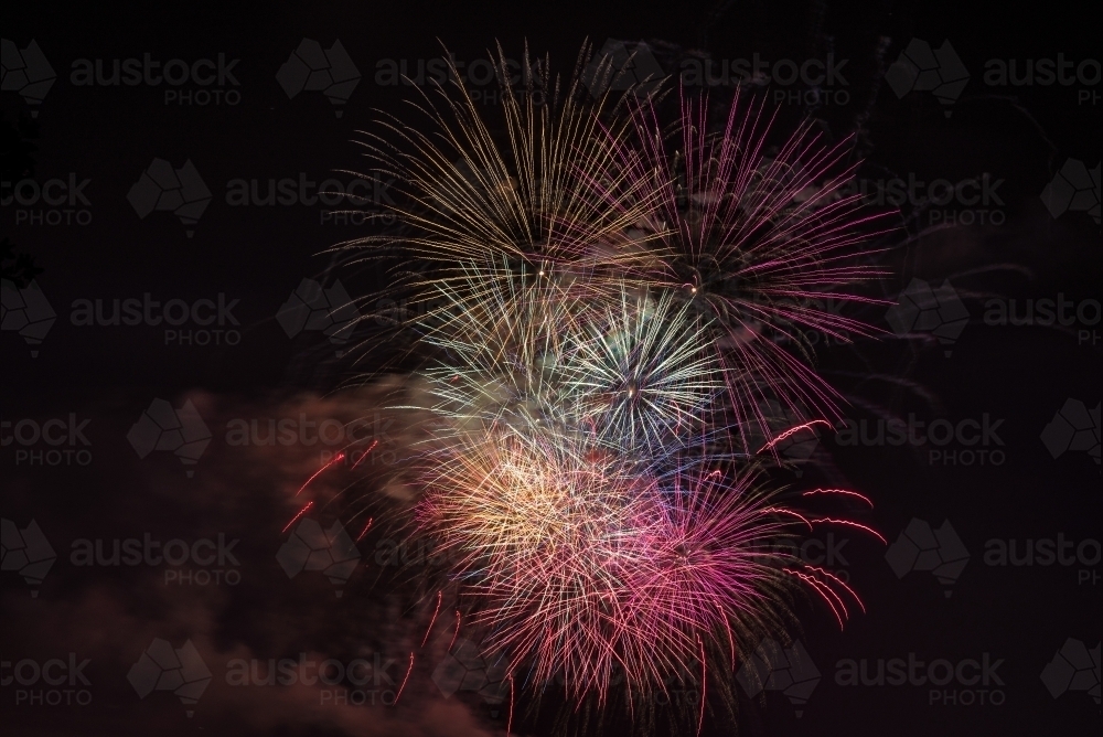 Image of Fireworks colours explode in dark night sky Austockphoto