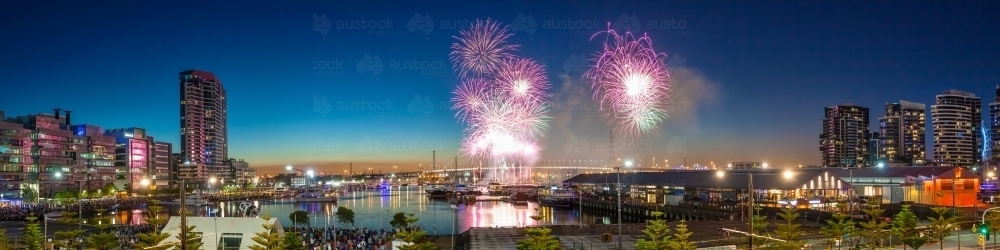 Fireworks going off in a twilight sky over a city marina. - Australian Stock Image
