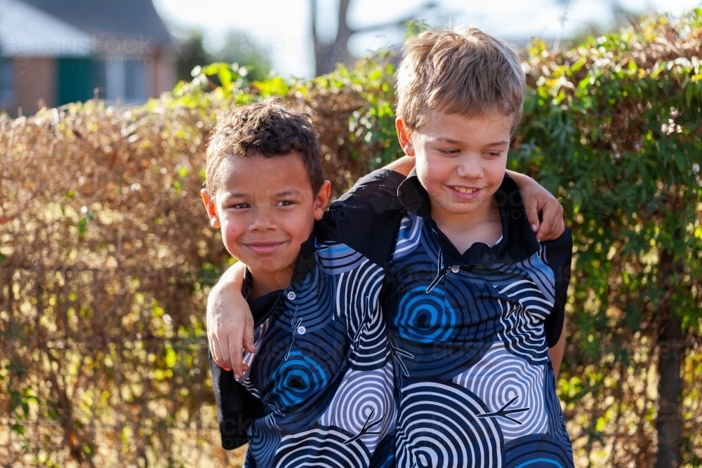 First Nations Australian brothers in backyard with arms around each other - Australian Stock Image