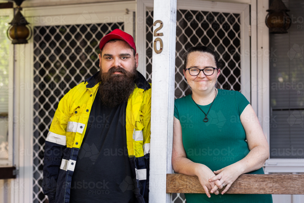 First Nations Australian husband and wife standing on front verandah of Aussie home - Australian Stock Image