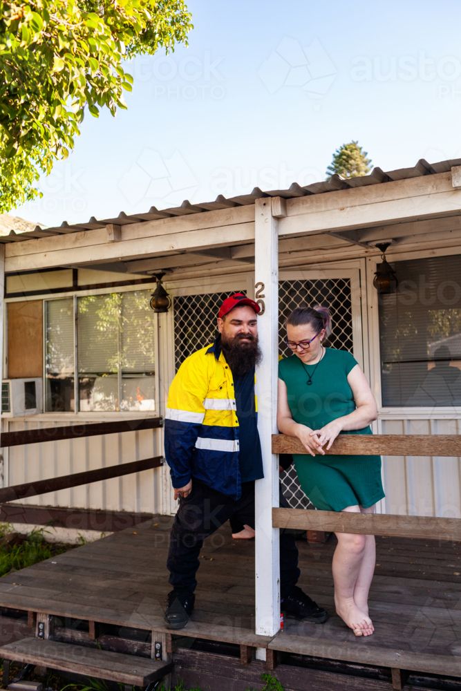 First Nations Australian husband and wife standing on front verandah of Aussie home - Australian Stock Image