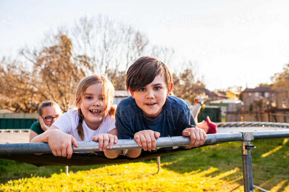 First Nations Australian kids lying on trampoline together in backyard - Australian Stock Image