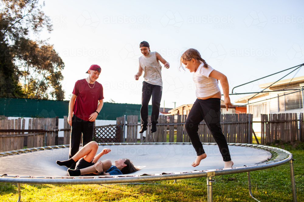 First Nations Australian Kids playing crack the egg jumping on trampoline in backyard - Australian Stock Image