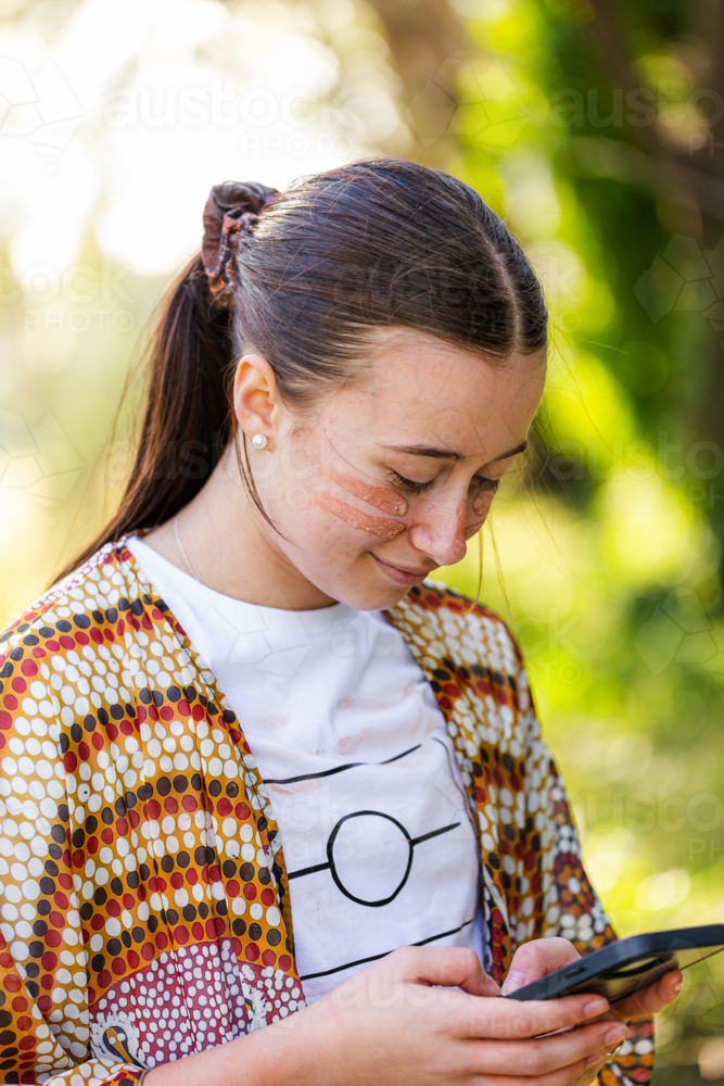 First Nations Australian teenager on mobile device using social media - Australian Stock Image
