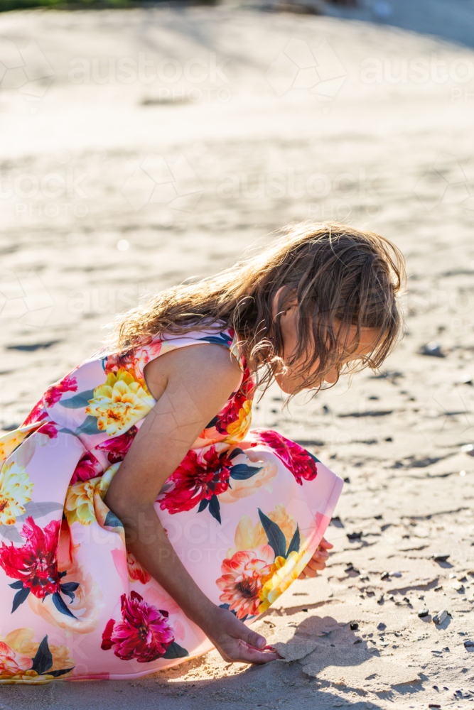 First Nations Australian Torres Strait Islander girl playing in the sand on windy day at the beach - Australian Stock Image