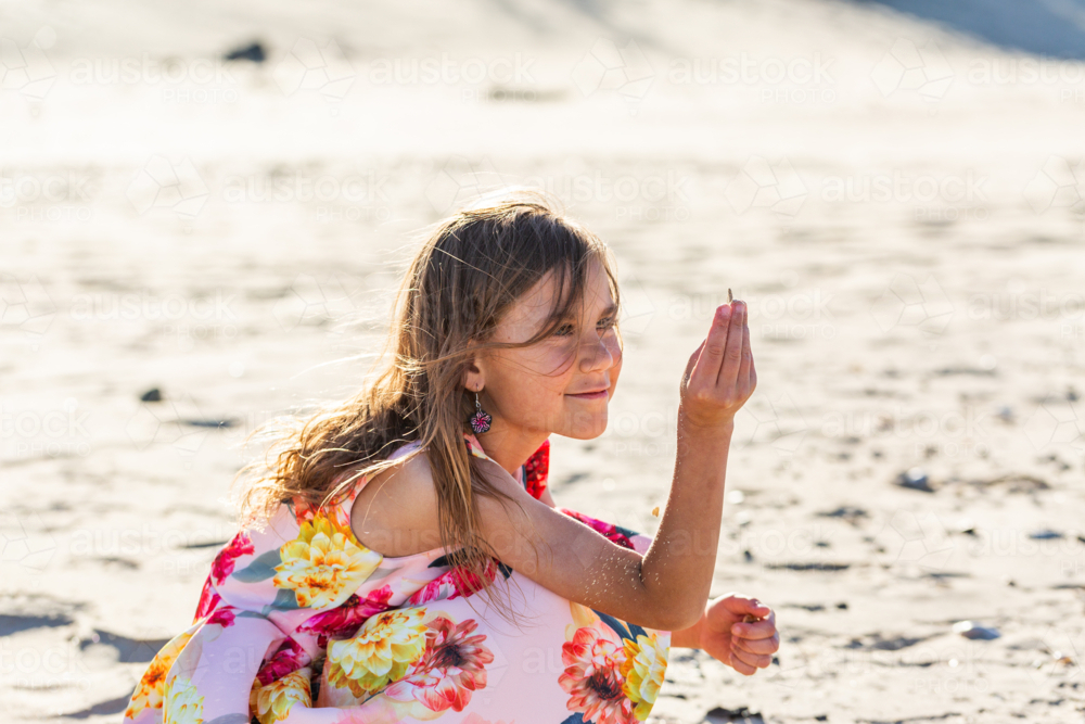 First Nations Australian Torres Strait Islander girl playing in the sand on windy day at the beach - Australian Stock Image