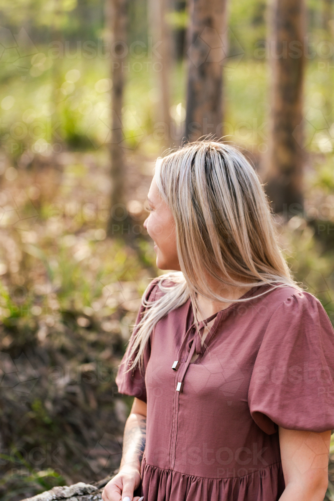First Nations Australian Wonnarua Aboriginal woman portrait in profile smiling in native bushland - Australian Stock Image