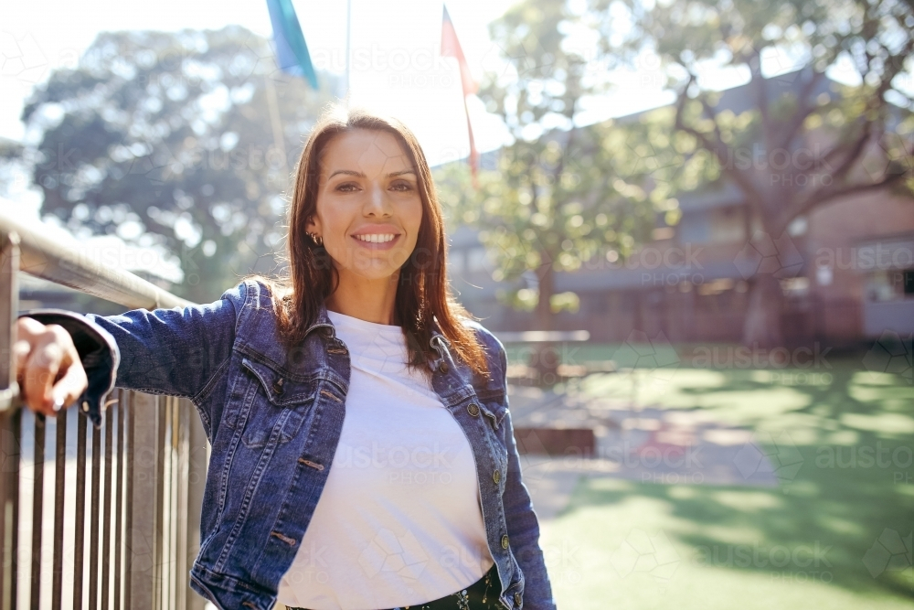 First Nations public school teacher leaning on the railings smiling - Australian Stock Image