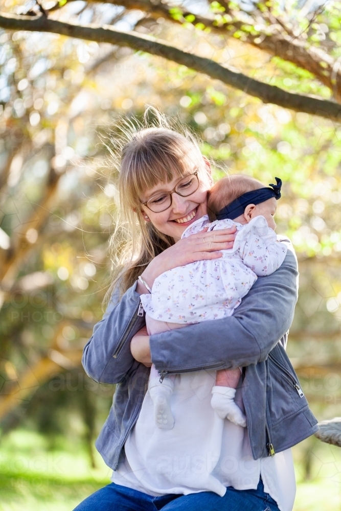 First time mum with newborn baby sitting outside - Australian Stock Image