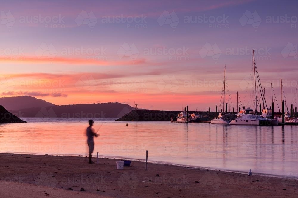 Fisherman at marina during twilight. - Australian Stock Image