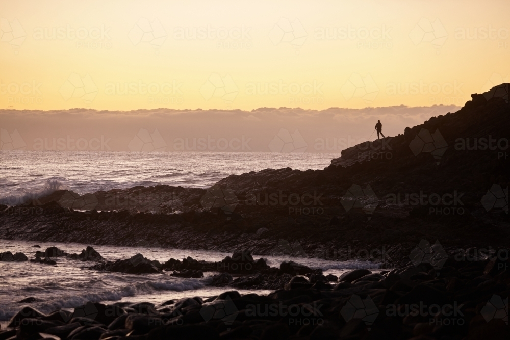 Fisherman fishing at coastal landscape on sunrise - Australian Stock Image