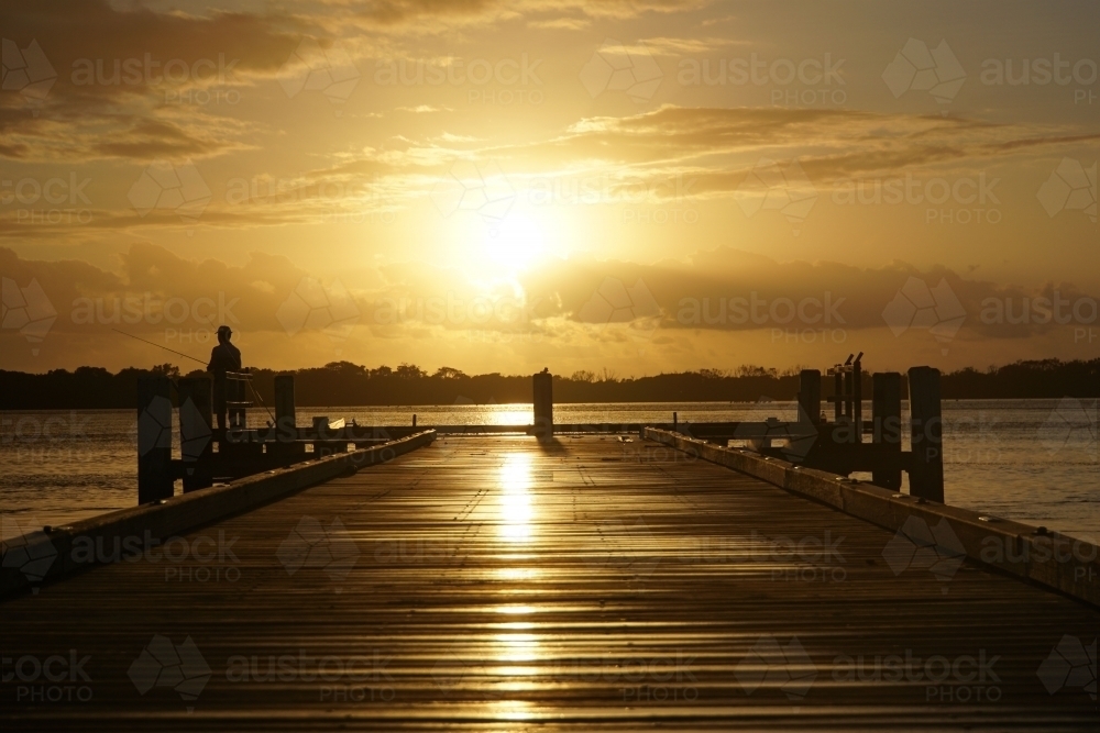 Fisherman on jetty at sunrise - Australian Stock Image
