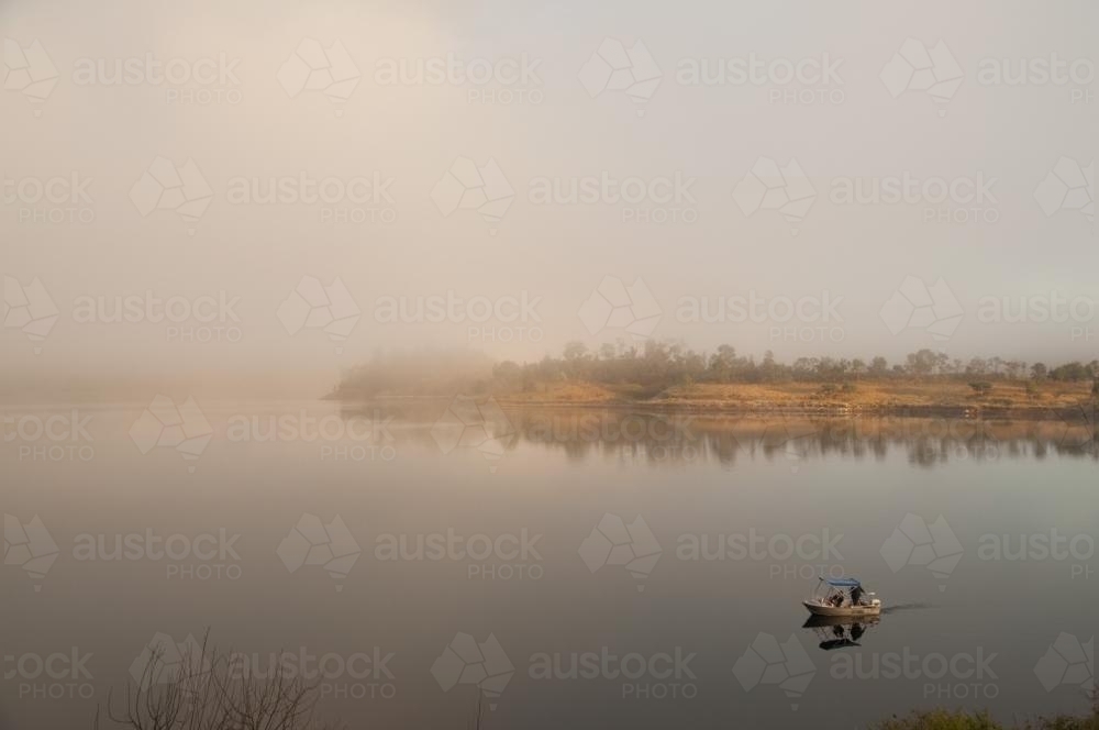 Fishermen in a tinny on a misty lake - Australian Stock Image