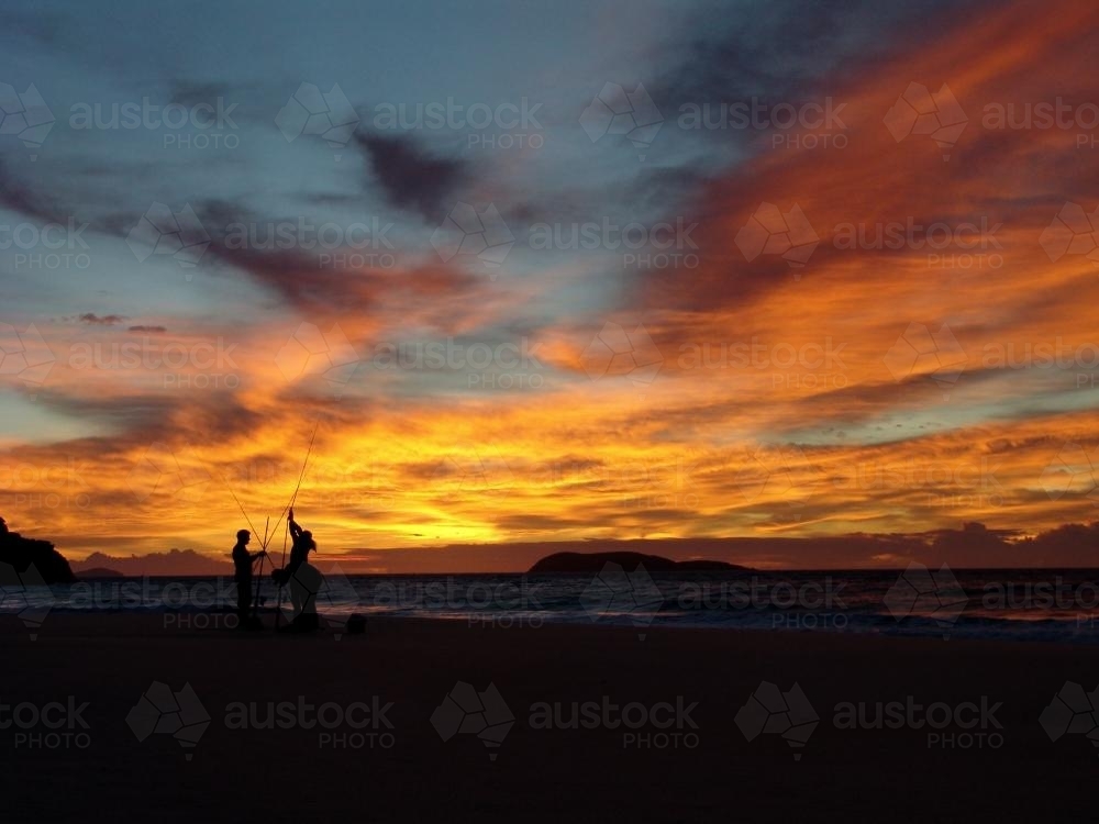 Fishermen silhouetted against yellow/orange sunset Nelsons Bay - Australian Stock Image