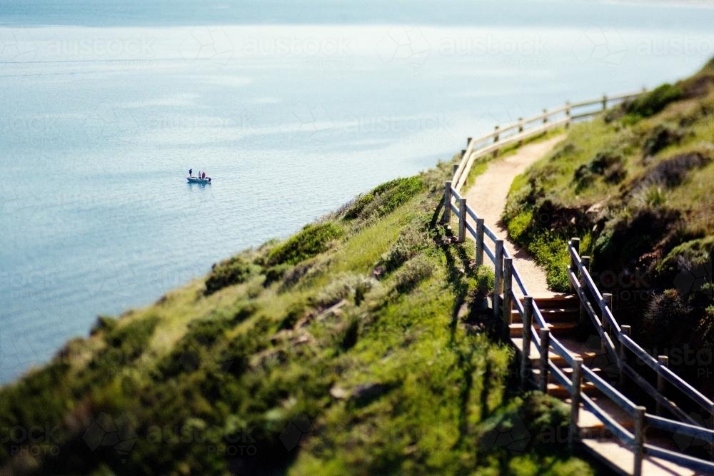 Fishing boat on the ocean with a coastal walkway - Australian Stock Image