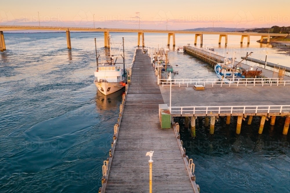 Image of Fishing boats docked at a jetty at sunset - Austockphoto