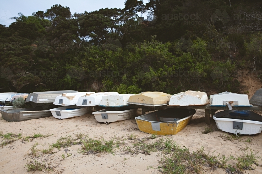 Fishing boats stacked on dry land on a beach at mornington - Australian Stock Image