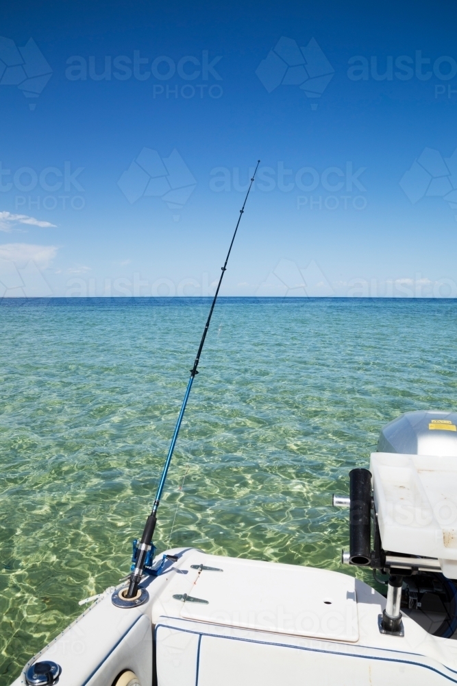 fishing rod and boat in calm water - Australian Stock Image
