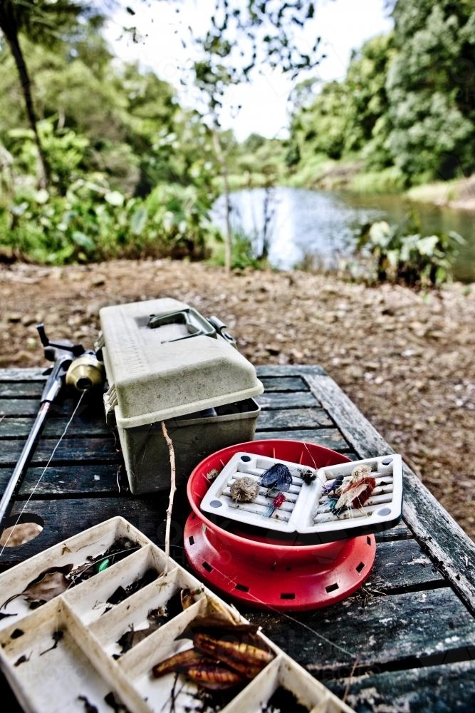 Fishing Tackle and box on Table with river in background - Australian Stock Image