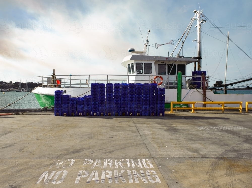 Fishing trawler and blue crates at a dock - Australian Stock Image