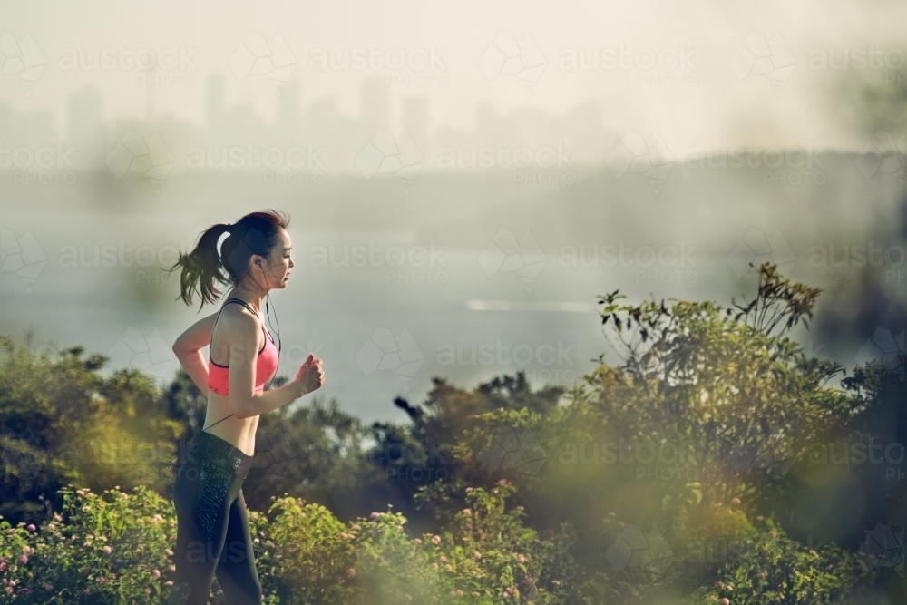 Fit Asian woman running for morning exercise - Australian Stock Image