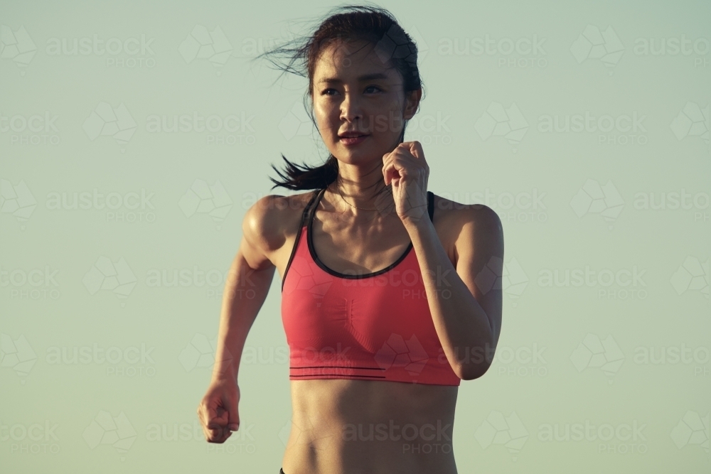 Fit Asian woman running for morning exercise - Australian Stock Image