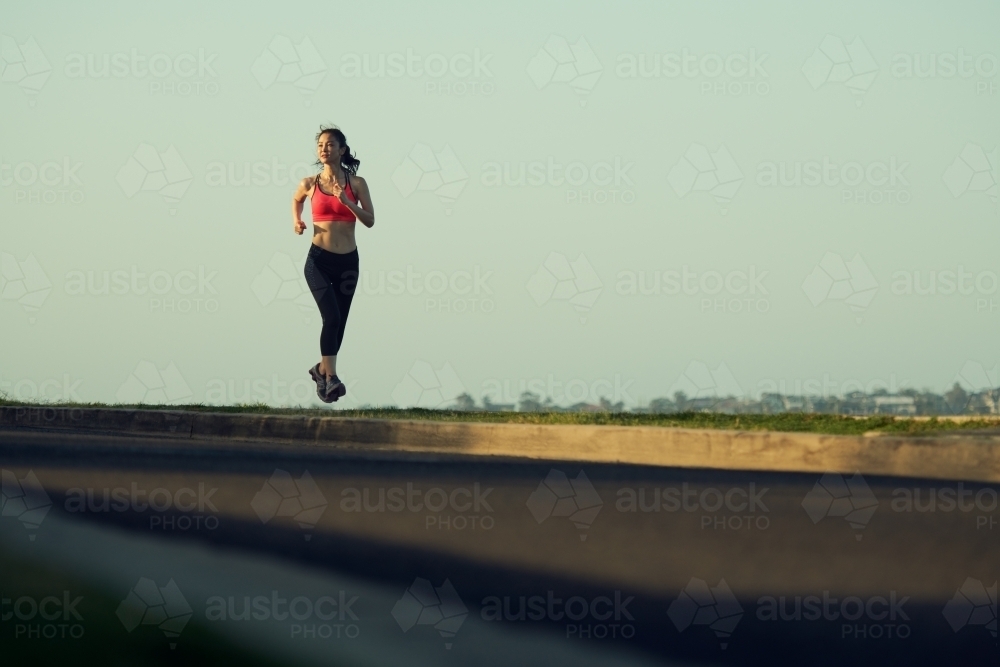 Fit Asian woman running for morning exercise - Australian Stock Image