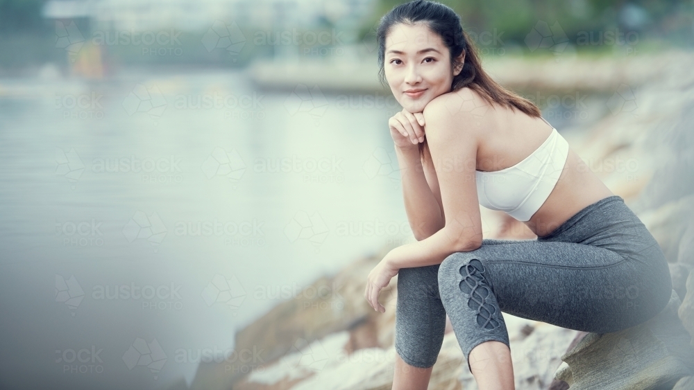 Happy Asian woman resting after morning workout - Australian Stock Image