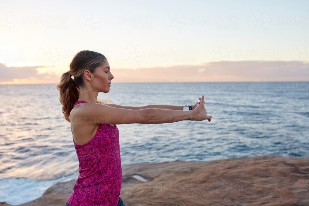Fitness woman warming up and stretching at coastal headland - Australian Stock Image